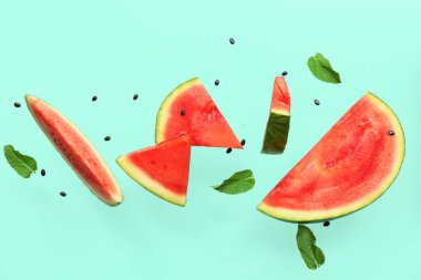 Uçan taze karpuz parçaları tohumlar ve turkuaz arka planda nane şekeri.