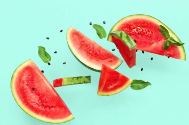 Uçan taze karpuz parçaları tohumlar ve turkuaz arka planda nane şekeri.