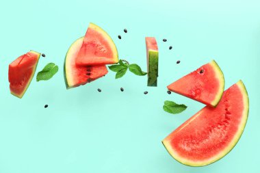 Uçan taze karpuz parçaları ve arkaplanda nane ve tohumlar.
