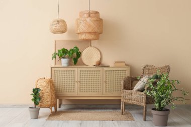 Yastıklı hasır koltuk, oturma odasında çekmeceler ve lambalar.