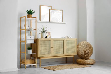 Ahşap çekmeceler ve raflar. Oturma odasının iç tarafındaki beyaz duvarın yanında bitkiler var.