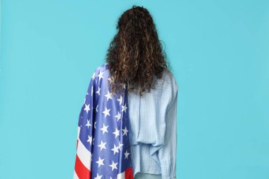 Mavi arka planda Amerikan bayrağı olan güzel bir Afro-Amerikalı kadın.