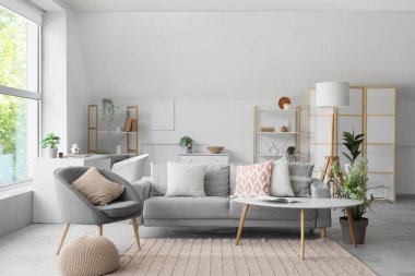 Gri koltuklu, koltuklu ve yumuşak yastıklı bir oturma odası.