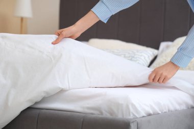 Yatak odasında yatak yapan genç kadın, yakın plan.
