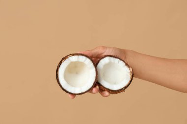 Kahverengi arka planda taze hindistan cevizi olan kadın eli.