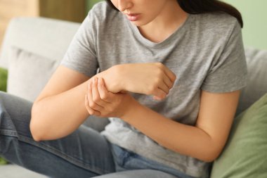 Evdeki kanepede bileğindeki ağrıdan muzdarip genç kadın, yakın plan.