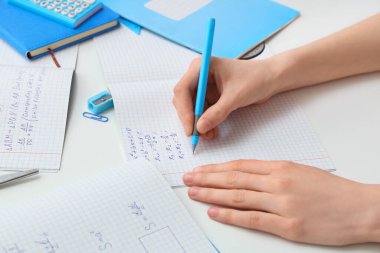 Fotokopi kitaplarında matematik formülleri yazan kadın ve arka planda kırtasiye, yakın plan