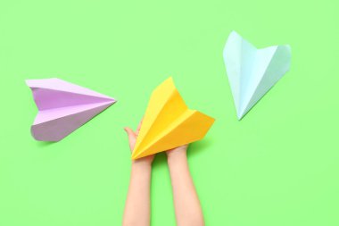 Yeşil arka planda kağıt uçaklar olan çocuk elleri
