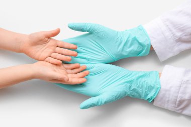 Çocuk ve doktorun elleri beyaz arkaplanda, yakın plan.