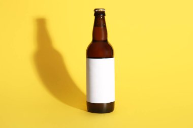 Sarı arka planda bir şişe soğuk bira.