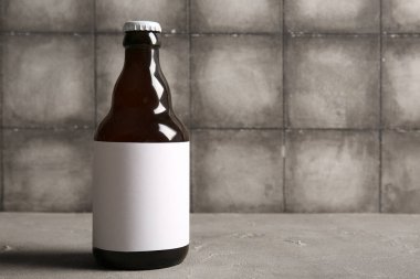 Gri masada bir şişe soğuk bira.