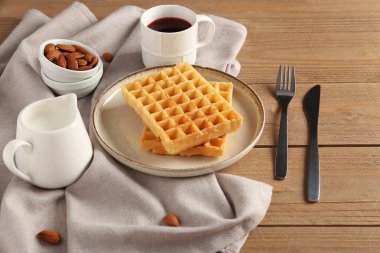Lezzetli Belçika waffle 'ı, badem ve ahşap arka planda bir fincan kahve.