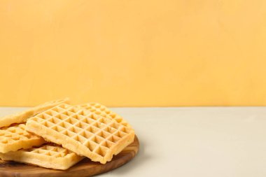 Sarı arka planda lezzetli Belçika waffle 'ları olan ahşap tahta tahta.