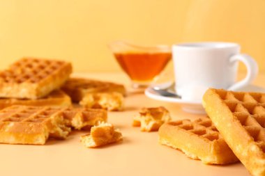 Lezzetli Belçika waffleları, tatlı bal teknesi ve sarı arka planda bir fincan kahve.