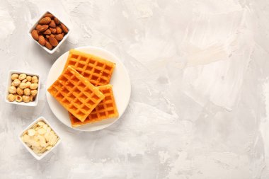 Lezzetli Belçika waffle tabağı ve gri arka planda farklı fındıklar.