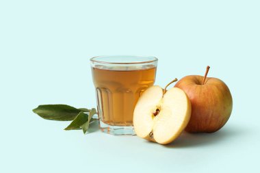 Mavi arka planda bir bardak taze elma suyu.