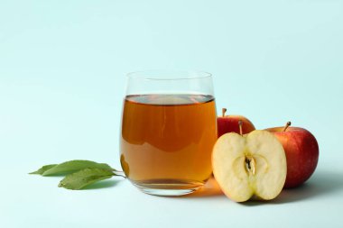 Mavi arka planda bir bardak taze elma suyu.