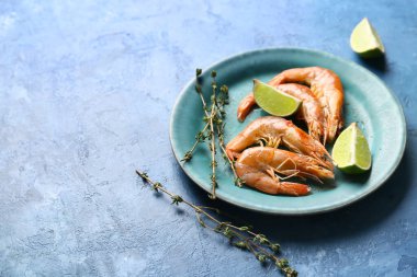 Lezzetli haşlanmış karides tabağı ve mavi arka planda limon.