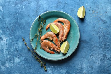 Lezzetli haşlanmış karides tabağı ve mavi arka planda limon.