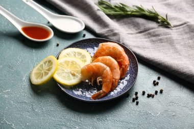 Lezzetli kaynamış karides tabağı ve yeşil arka planda kaşıklar dolusu sos.