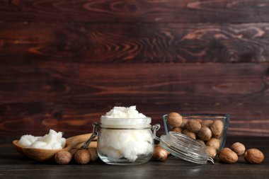 Cam kavanoz, ahşap masada tereyağı ve fındık.