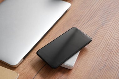 Kablosuz şarj aleti ve ahşap masada dizüstü bilgisayarı olan modern bir cep telefonu.