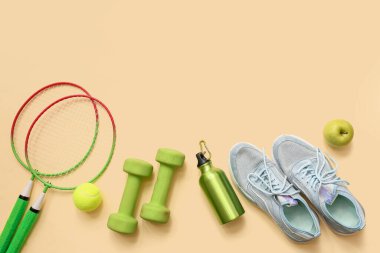 Bej arka planda spor ayakkabıları, elma ve spor aletleri