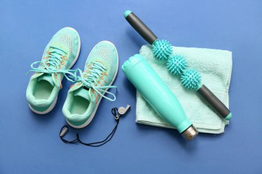 Mavi arka planda spor ayakkabıları, havlu ve spor aletleri