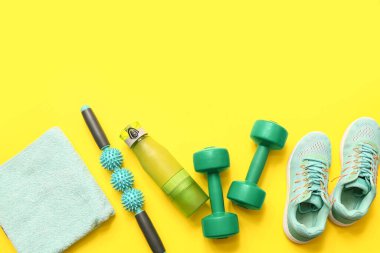 Sarı arka planda spor ayakkabıları, havlu ve spor malzemeleri.