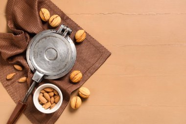 Tasty walnut shaped cookies with boiled condensed milk, baking form and almonds on beige wooden table clipart