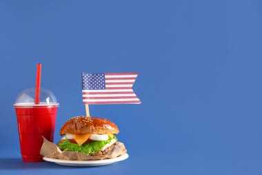 Amerikan bayrağı ve mavi arka planda kola ile lezzetli bir burger. Amerikan Bağımsızlık Günü kutlamaları