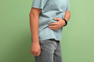 Yeşil arka planda apandisiti olan genç adam, yakın plan.