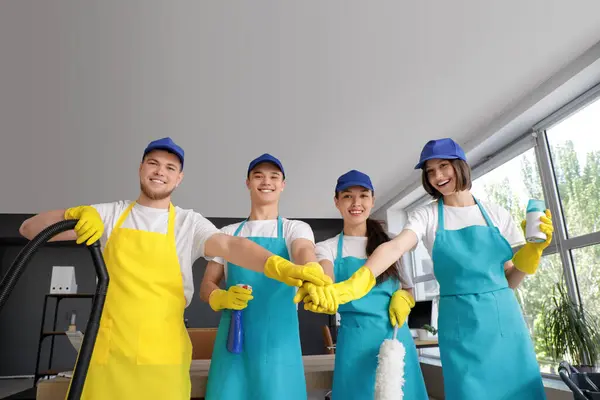 stock image Group of young janitors putting hands together in office