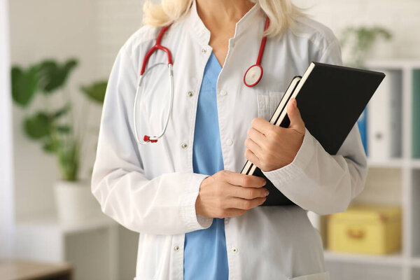 Female doctor with notebooks in clinic, closeup