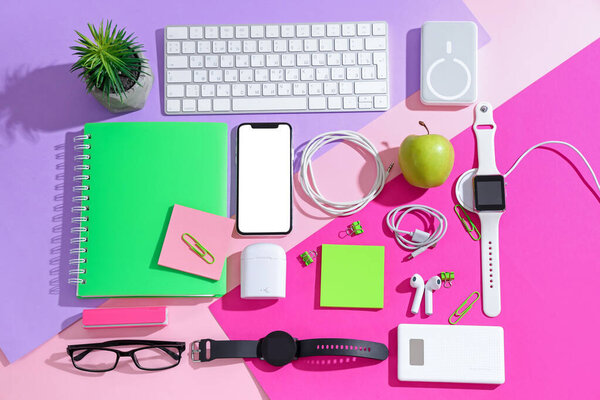 Композиция с различными современными гаджетами и канцелярскими принадлежностями на цветном фоне