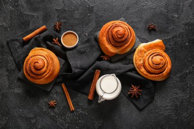 Yıldız anasonlu tarçınlı çörekler ve siyah arka planda bir sürahi süt.