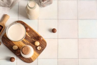 Beyaz fayanslı bir bardak ve bir şişe taze Macadamia sütü.