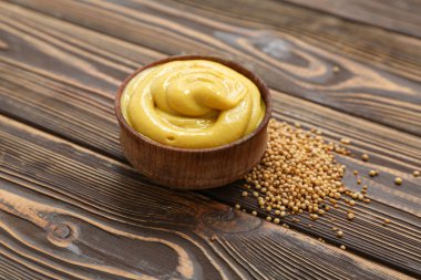 Kahverengi ahşap arka planda kremalı hardal ve çekirdekli kase.