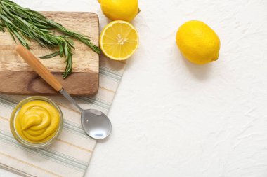 Beyaz arka planda kremalı hardal, kaşık ve limon kâsesi