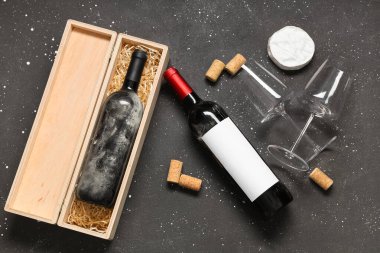 Siyah grunge arka planında şarap, mantar, bardaklar ve Camembert peyniri olan bir kutu.