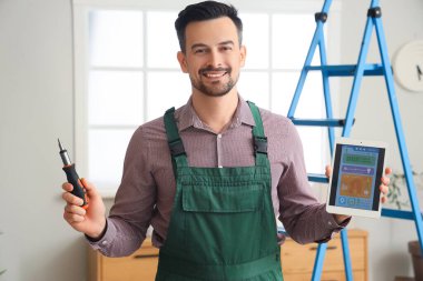 Alarm sistemi ve tornavidayla dolu tablet bilgisayarlı erkek işçi