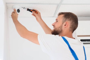 Erkek işçi odaya alarm sistemi kuruyor