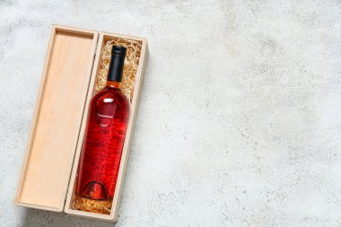 Gri arka planda kırmızı şarap şişesi olan tahta kutu.
