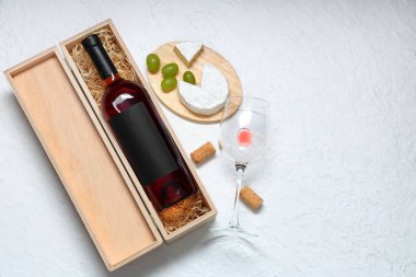 Bir şişe şarap, abur cubur ve beyaz arka planda bardak.