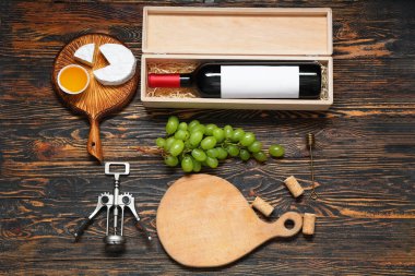 Kahverengi ahşap arka planda şarap, aperatif ve tirbuşon dolu bir kutu.