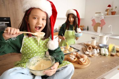 Küçük Asyalı kız Noel arifesinde mutfakta tarçınlı çörek için hamur hazırlıyor.