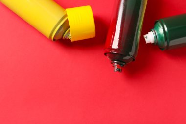 Kırmızı arkaplanda sprey boya kutuları