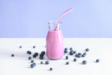 Mavi arka planda yabanmersinli bir şişe taze smoothie.