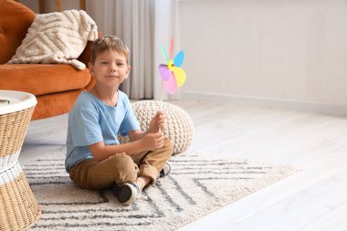 Oyuncak yel değirmenli şirin bir çocuk evde oturuyor.