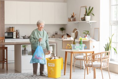 Mutfakta çöp torbası temizleyen yaşlı bir kadın.